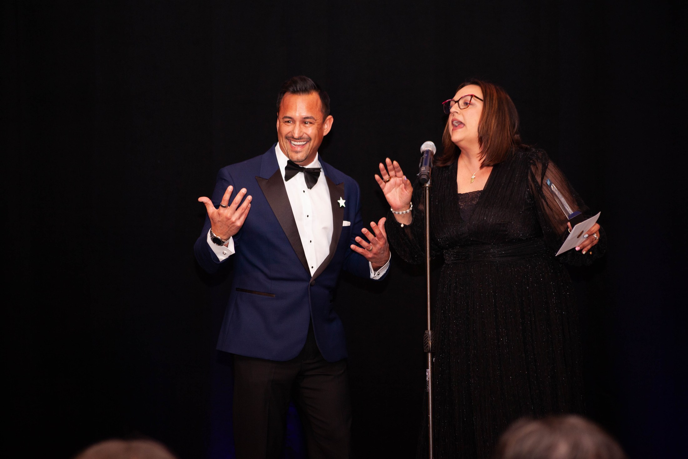 Two gala presenters sharing a joyful moment on stage